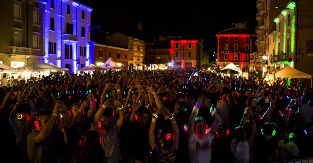 Place de nuit remplie de personnes avec casques silent disco