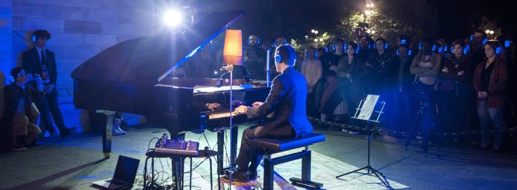 Pianiste en concert, public équipé de casques